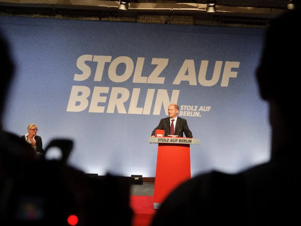 On the left side, there is a person. On the right side, there is a person. In the background, there...