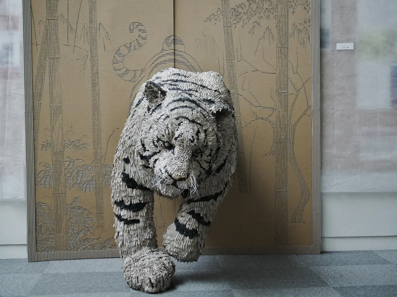 The picture consists of a replica of tiger made of cloth. On the right there is curtain and wall....
