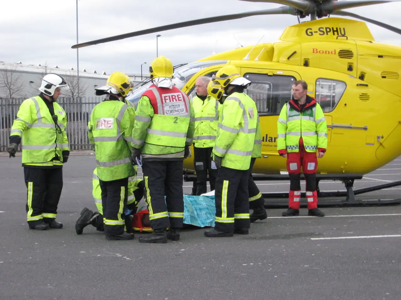 In this image there are group of workers who are wearing the green color jackets are standing on...