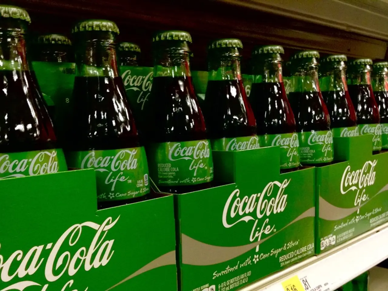 there are glass bottles placed in green cartons. on the carton coca cola life is written.