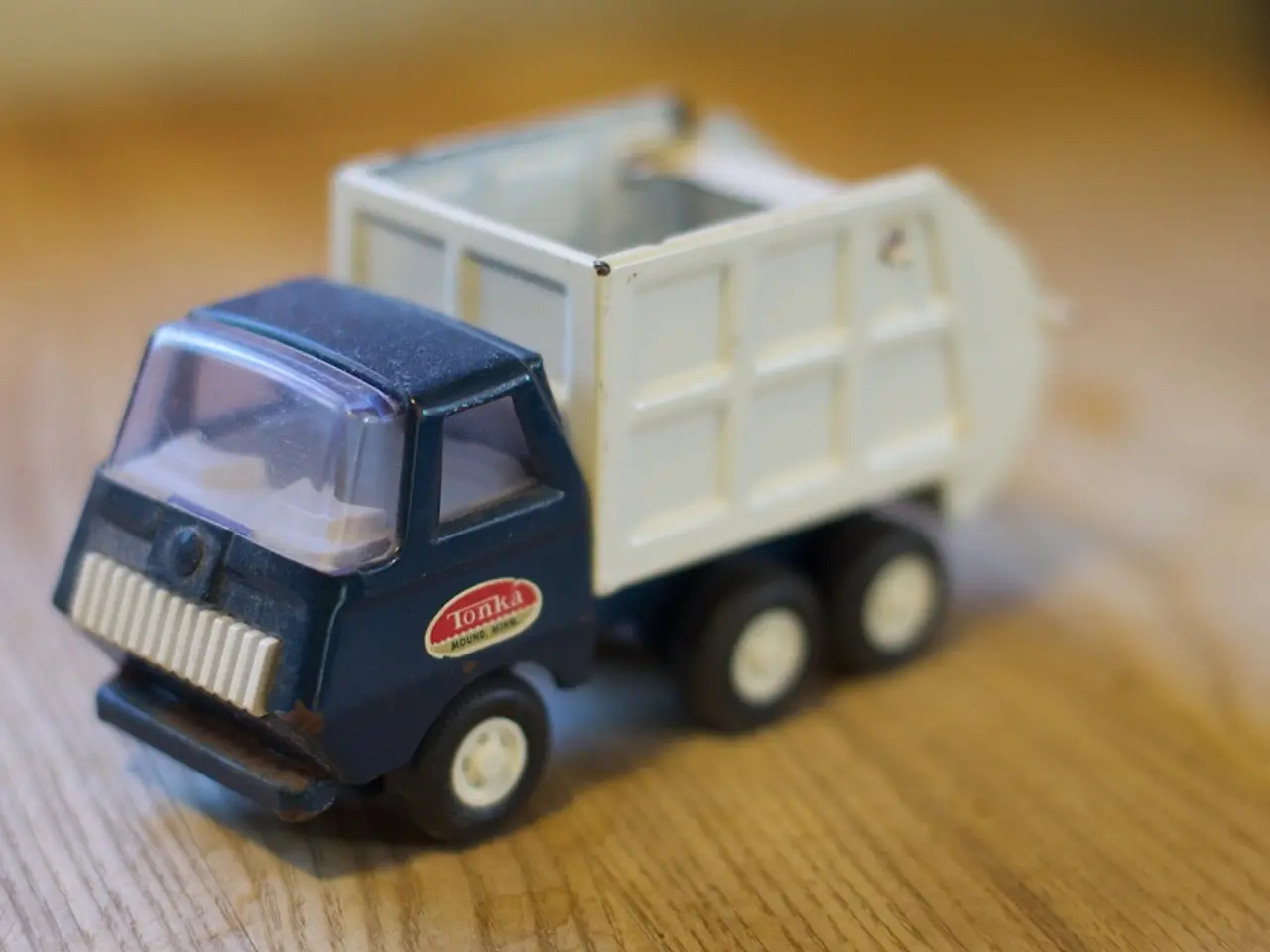 There is a toy vehicle present on a wooden floor as we can see in the middle of this image.