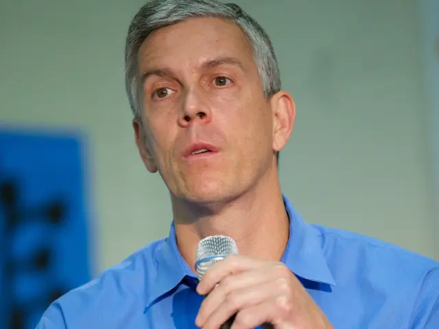 This picture shows a man seated and speaking with the help of a microphone in my hand