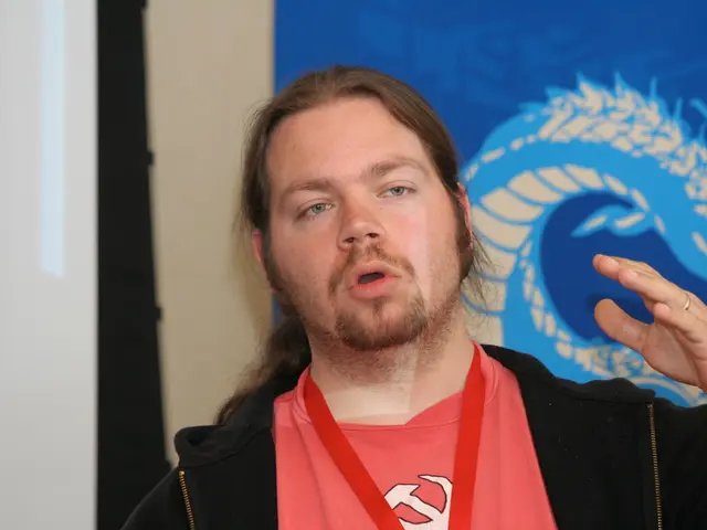 In the middle of this image, there is a person in black color jacket, wearing a ring and speaking....